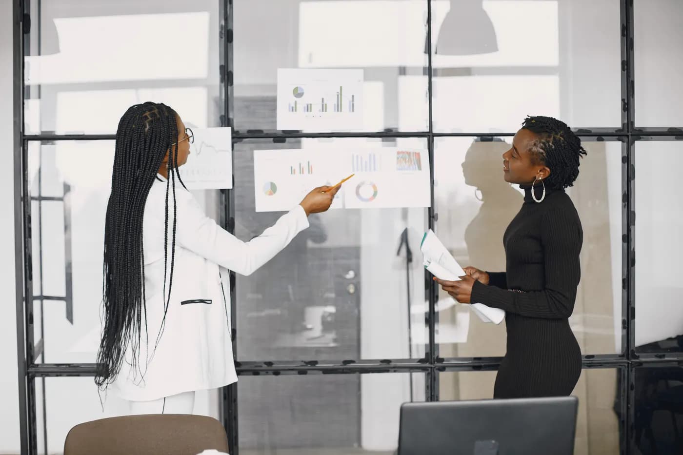 Two project managers reviewing project charts on a glass wall